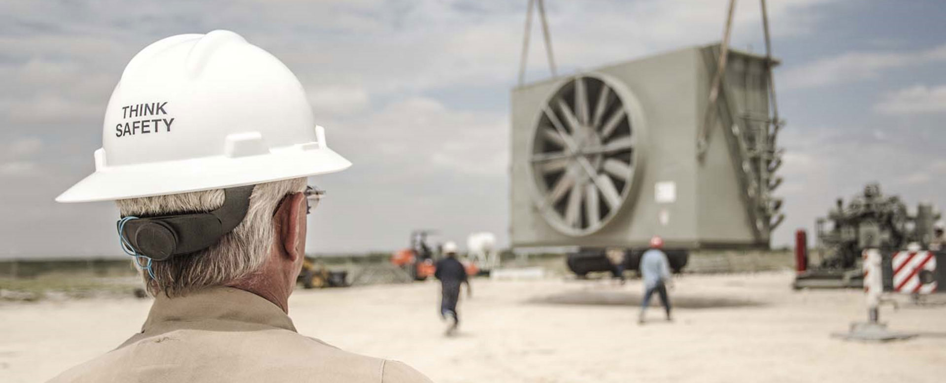 Engineer overlooking a work site wearing a helmet with text 'Think Safety'